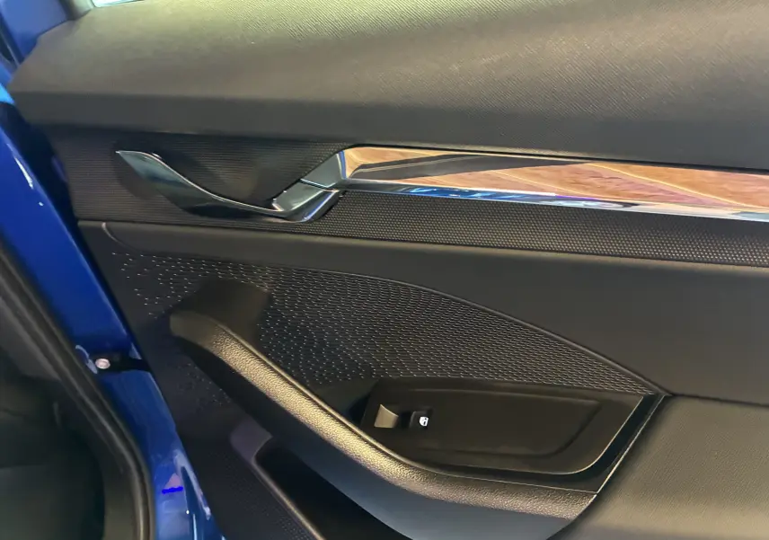 Détail de la porte intérieure côté gauche d’une Skoda Octavia Combi 2024 bleu, avec poignée chromée et bouton de verrouillage.