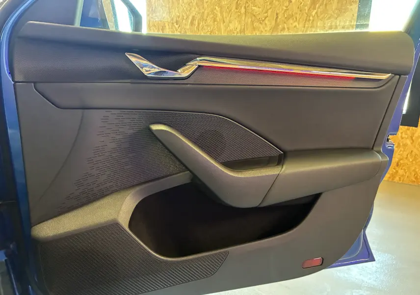 Vue intérieure de la porte avant droite bleu de la Skoda Octavia Combi 2024, avec garniture noire et insert chromé.