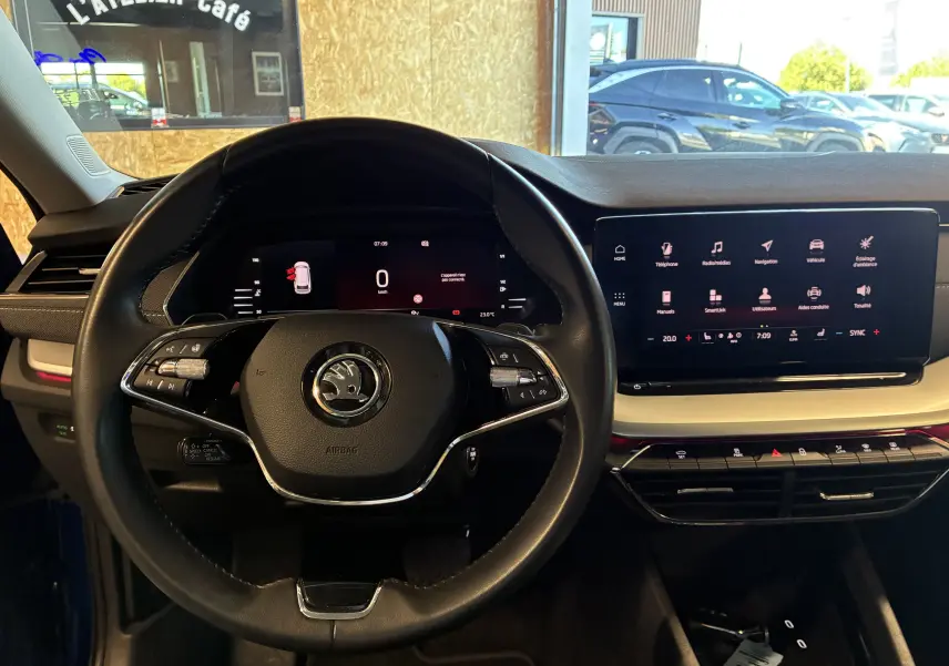 Vue intérieure centrée sur le volant et l'écran tactile du tableau de bord d'une Skoda Octavia Combi 2024.