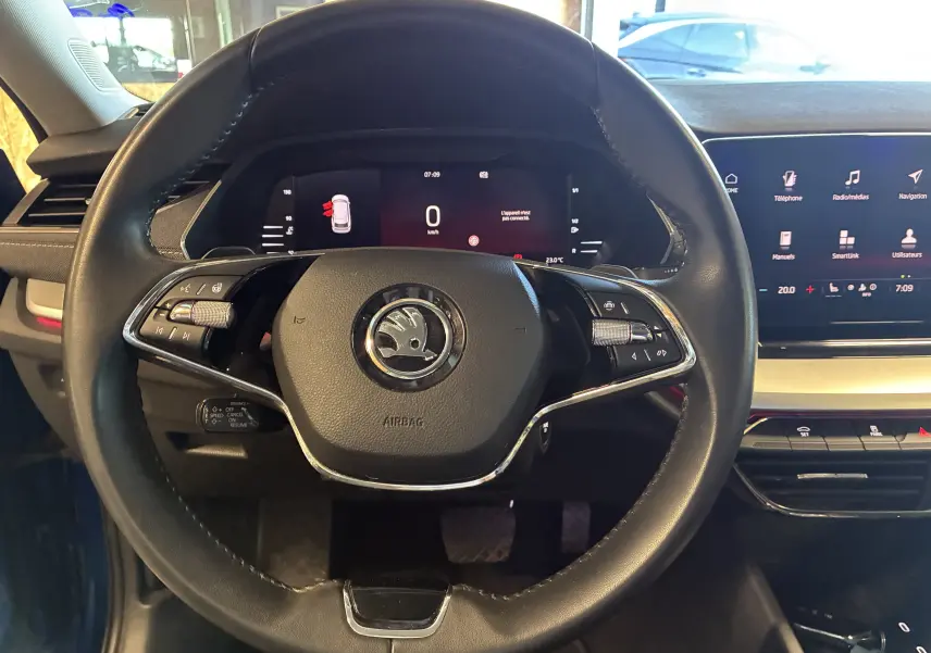 Vue centrée sur le volant noir du Skoda Octavia Combi 2024, avec tableau de bord digital et écran tactile visible à droite.