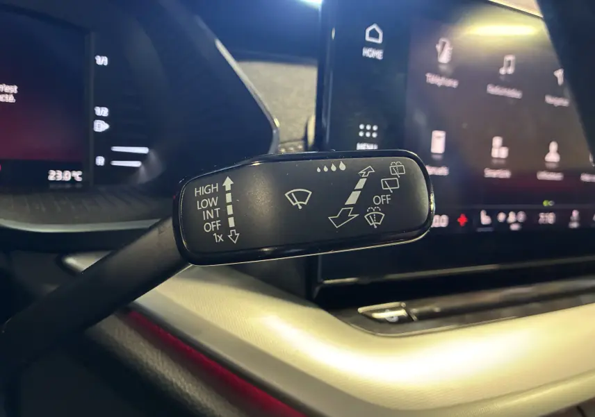 Gros plan sur la manette d'essuie-glace intérieure de la Skoda Octavia Combi 2024, avec tableau de bord et écran tactile en arrière-plan.
