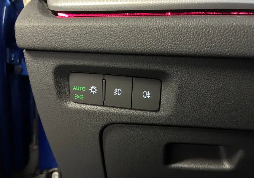 Gros plan sur les commandes d’éclairage avec mode automatique activé, dans un Skoda Octavia Combi bleu 2024.