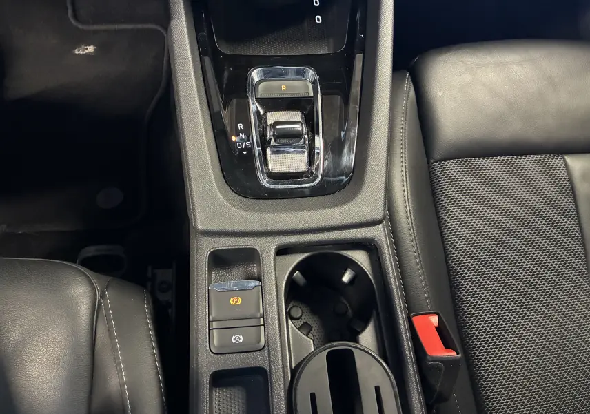Vue rapprochée de la console centrale noire de la Skoda Octavia Combi 2024 avec levier de vitesse DSG et porte-gobelets.