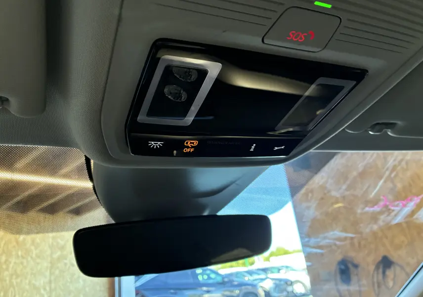 Vue intérieure du plafond avant d'une Skoda Octavia Combi 2024 bleu, avec commandes d'éclairage et bouton SOS éclairé.