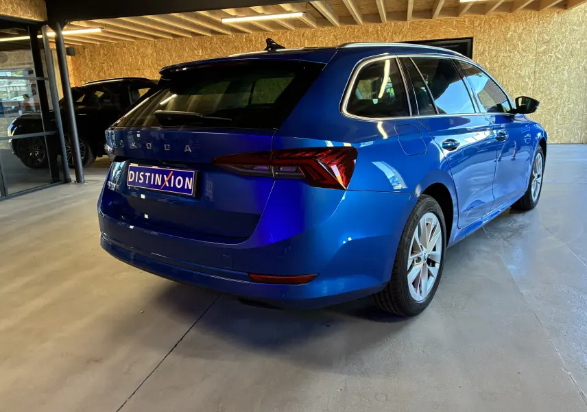 Vue 3/4 arrière droite d'une Skoda Octavia Combi 2024 bleu métallisé, avec feux arrière LED et jantes alliage.