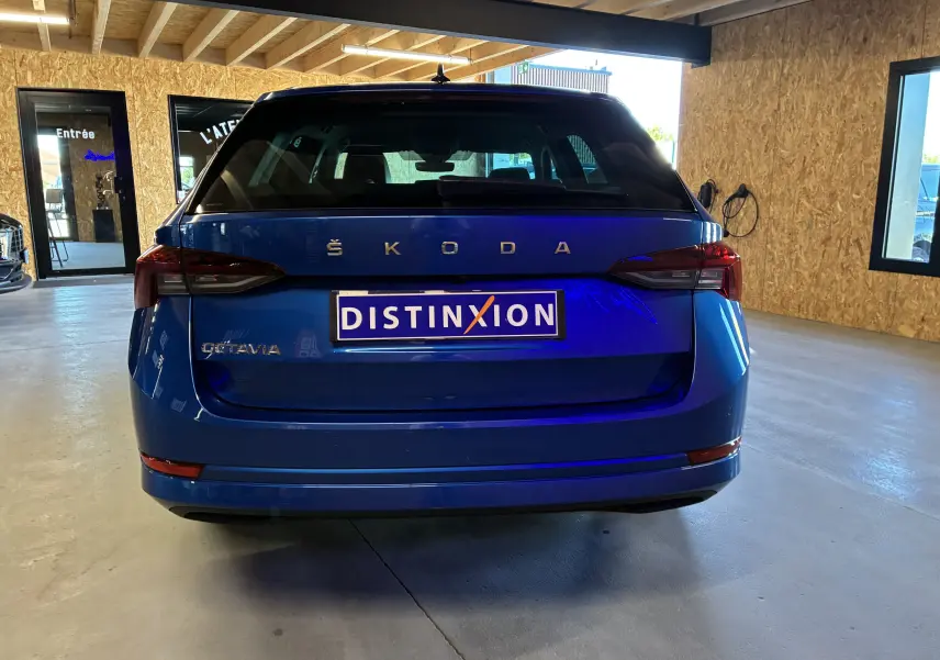 Vue arrière d'une Skoda Octavia Combi bleu 2024 avec feux LED et plaque Distinxion dans un garage.