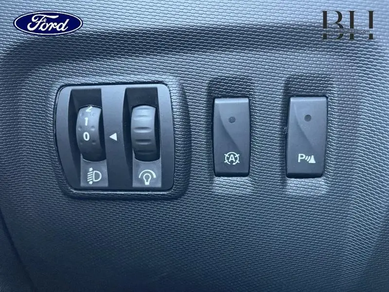 Gros plan sur les commandes d’éclairage et d’aide à la conduite du tableau de bord d’un Renault Captur beige avec toit noir.