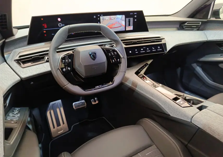 Intérieur moderne du Peugeot 3008 GT 2025, vue cockpit avec volant cuir, écran tactile large et console centrale grise.