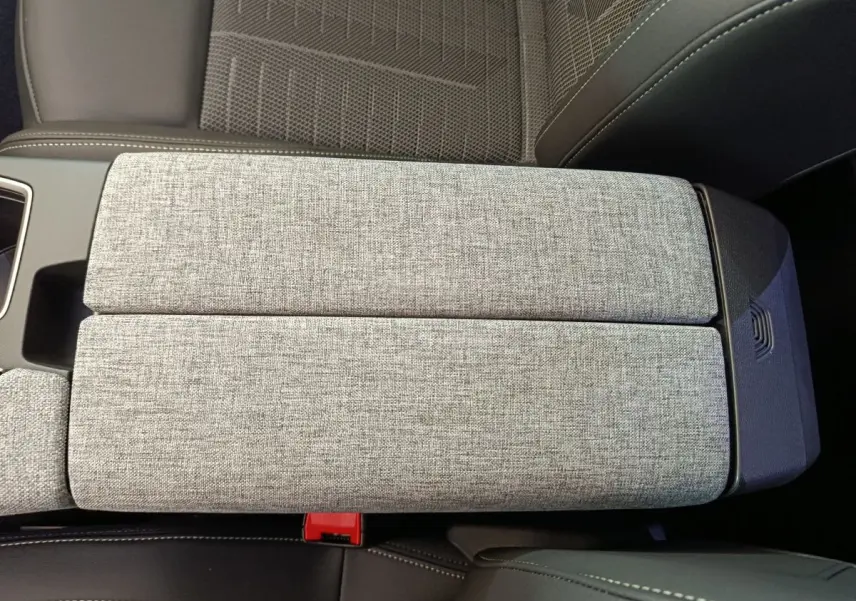 Accoudoir central gris clair en tissu avec siège noir en cuir partiel dans Peugeot 3008 2025 vue intérieure rapprochée
