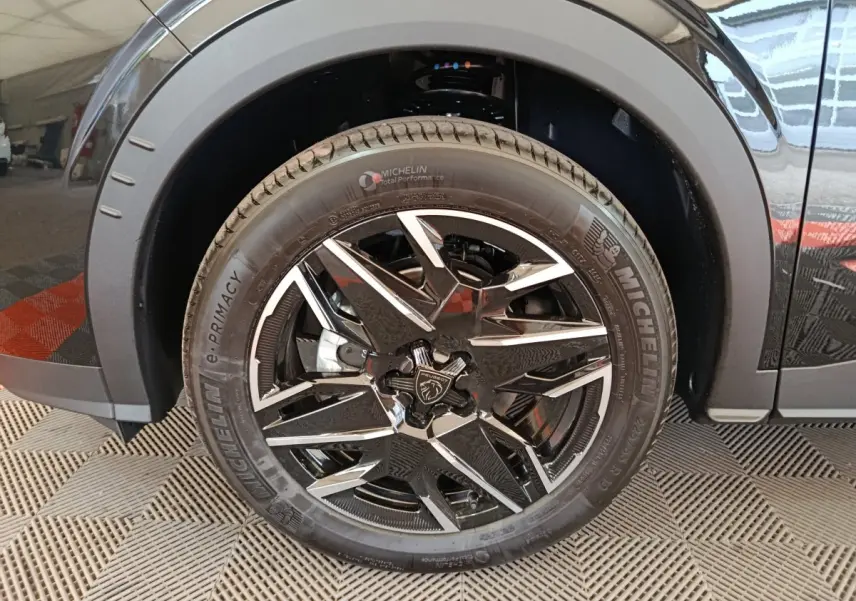 Gros plan sur la roue avant gauche noire du Peugeot 3008 1.2 HYBRID 145 E-DCS6 GT avec jante alliage bicolore.