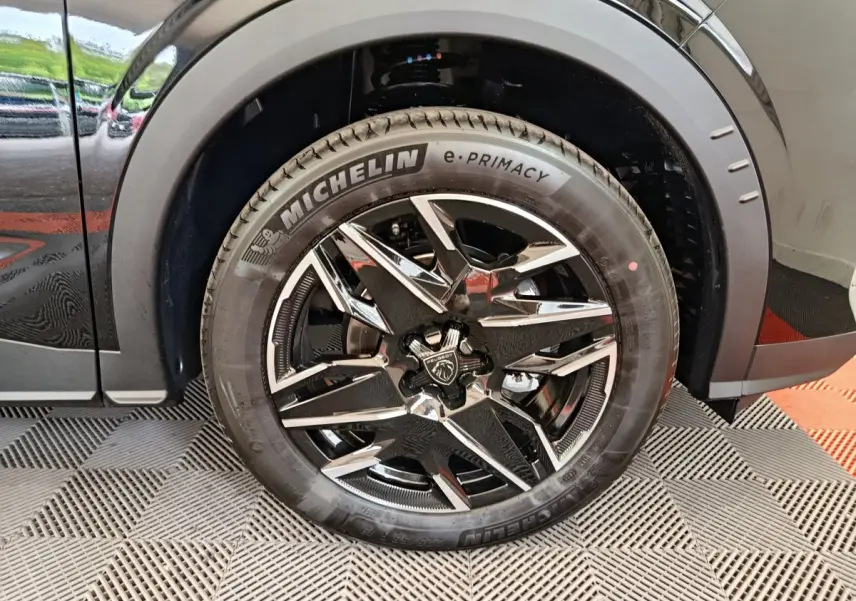 Gros plan sur la roue avant gauche du Peugeot 3008 noir, mettant en valeur la jante alliage au design moderne et le pneu Michelin e-Primacy.