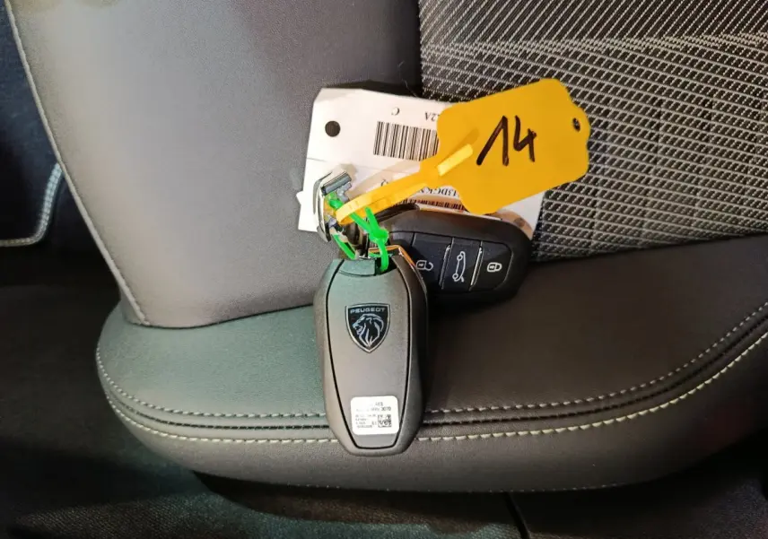 Gros plan sur la clé Peugeot noire posée sur un siège en cuir noir avec surpiqûres contrastantes.