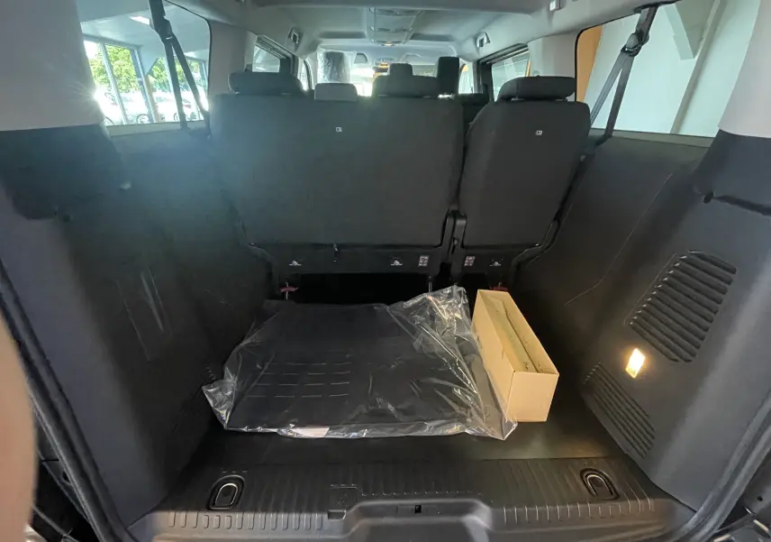 Vue intérieure arrière du coffre noir du Peugeot Traveller 2026 avec sièges rabattus et éclairage latéral allumé.
