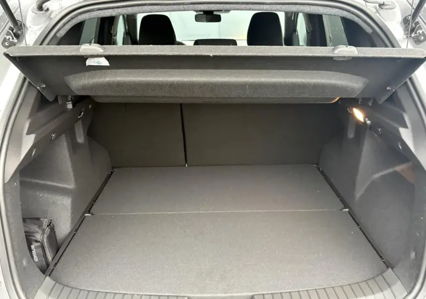 Coffre ouvert du Dacia Duster gris schiste 2026, vue arrière montrant l'espace de chargement avec cache-bagages déployé.