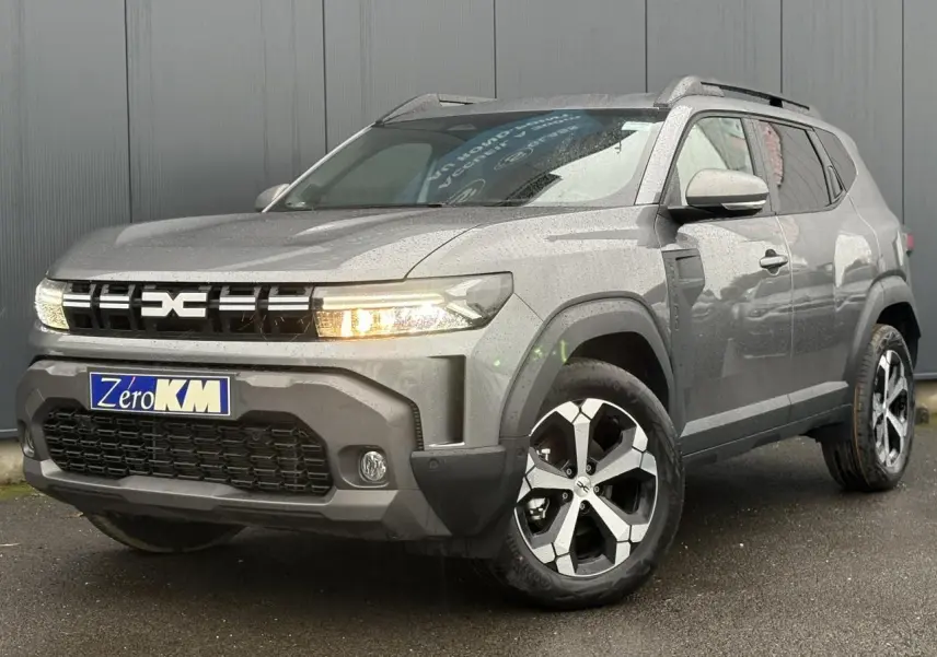 SUV Dacia Duster gris schiste en 3/4 avant droit, avec jantes alliage diamantées et signature lumineuse LED allumée.