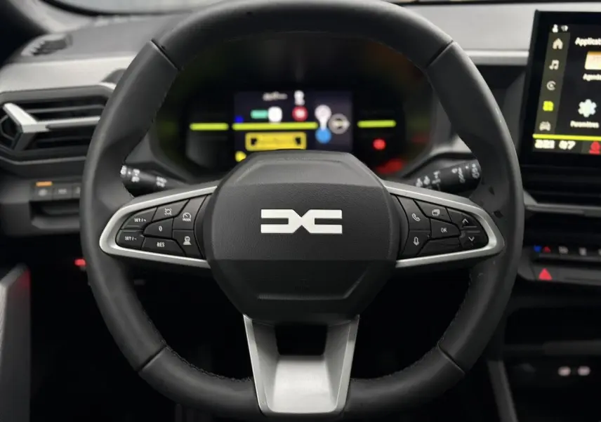 Vue rapprochée du volant noir du Dacia Duster 2026 avec commandes intégrées et tableau de bord digital en arrière-plan.