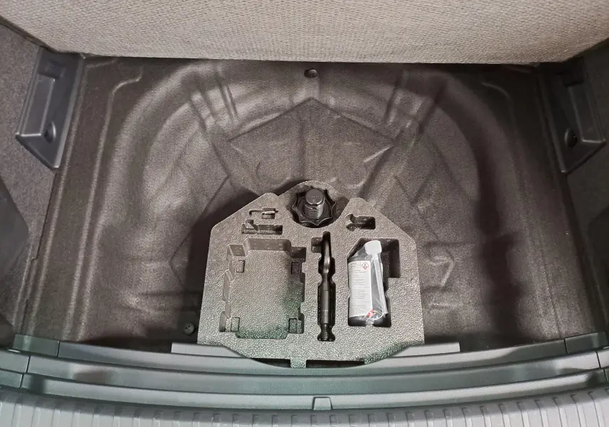 Vue plongeante sur le coffre ouvert du SEAT Ateca 2025, montrant le rangement sous plancher avec kit de réparation.
