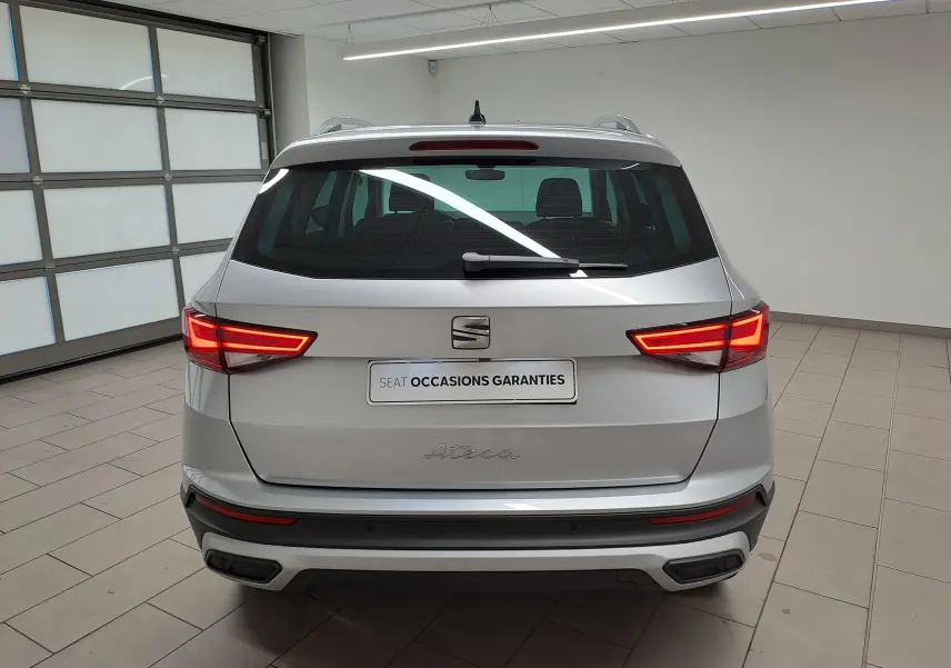 Vue arrière d'un SEAT Ateca 2.0 TDI 150 DSG7 Copa argent métallisé avec feux allumés dans un garage.