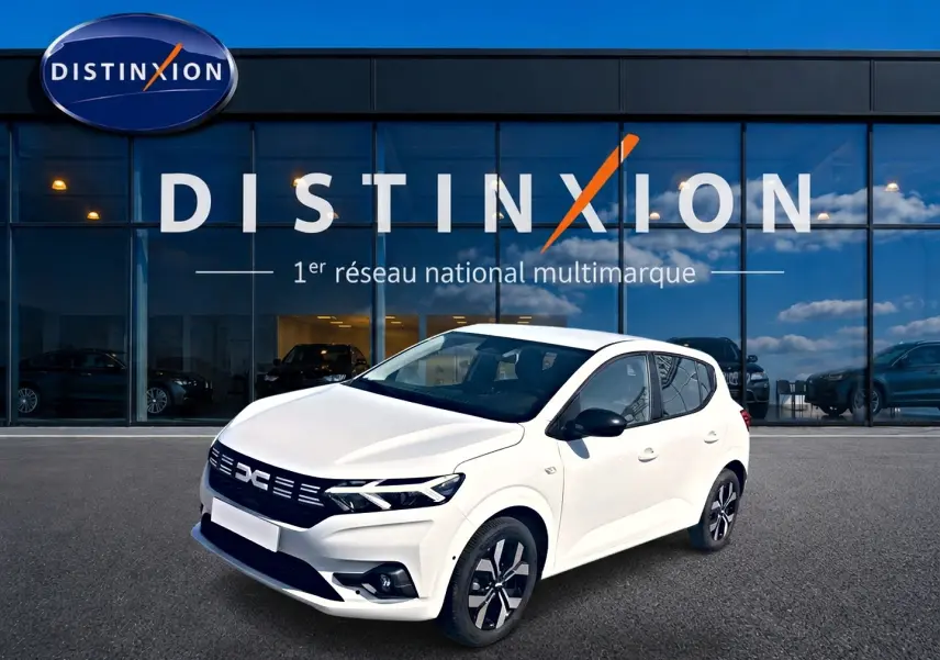 Dacia Sandero 1.0 TCe 90 Journey blanc vue 3/4 avant avec jantes alu et rétroviseurs noirs devant showroom Distinxion.