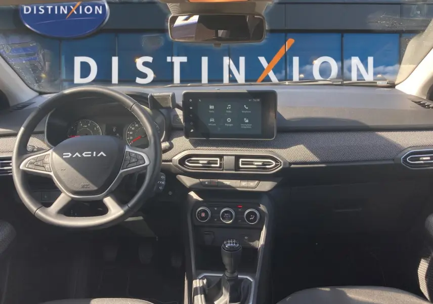 Vue intérieure avant de la Dacia Sandero 2025, tableau de bord noir avec écran tactile et volant multifonctions.