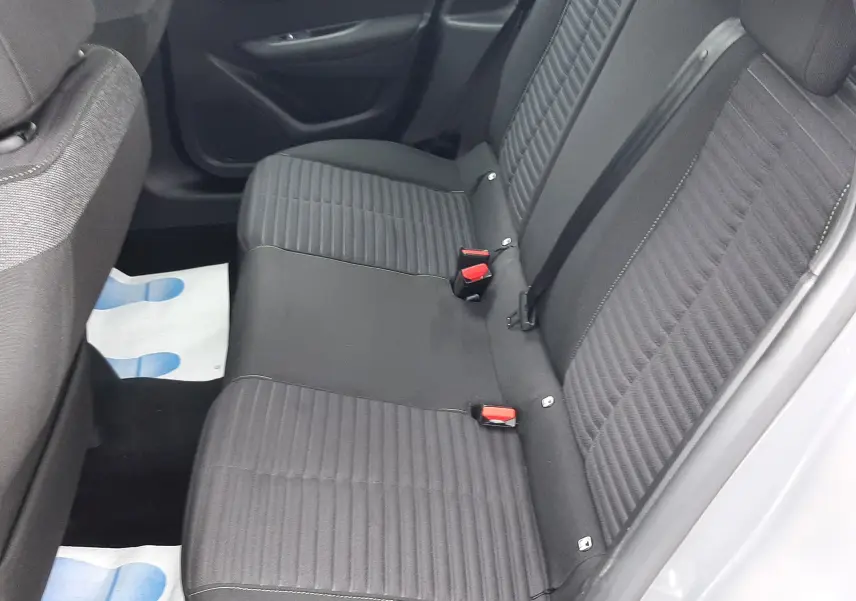 Vue intérieure côté droit des sièges arrière en tissu gris de la Peugeot 208 1.2 PureTech 2024, porte ouverte.