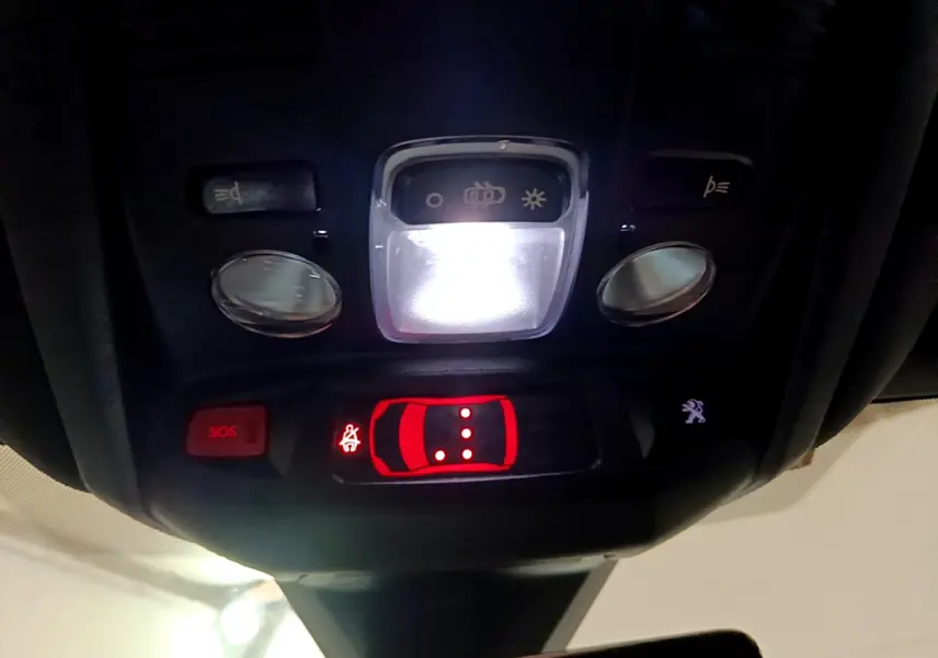Vue en gros plan du plafonnier intérieur avec commandes lumineuses et bouton SOS du Peugeot 3008 noir 2023.