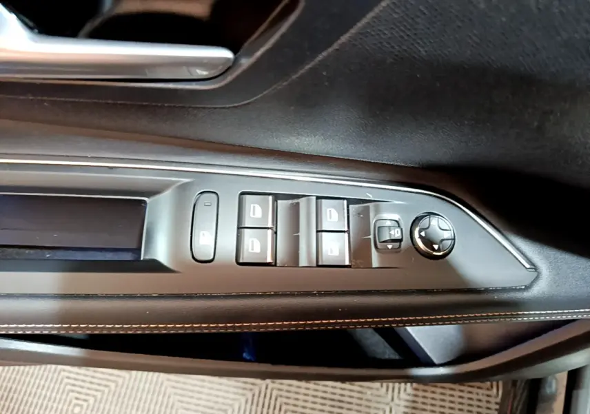 Gros plan sur la commande des vitres et rétroviseurs côté conducteur du Peugeot 3008 GT noir de 2023.