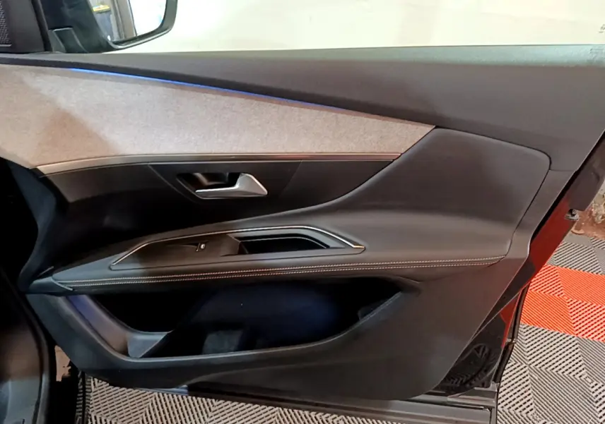 Vue intérieure côté gauche de la porte avant noire du Peugeot 3008 GT 2023 avec garniture tissu et coutures contrastées.