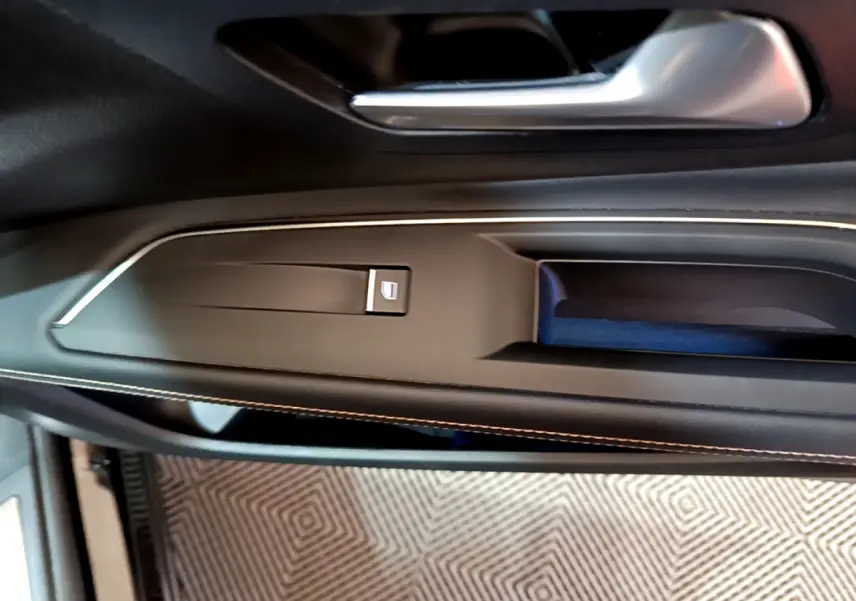 Poignée de porte intérieure côté gauche du Peugeot 3008 noir 2023 avec bouton de lève-vitre et surpiqûres contrastées.