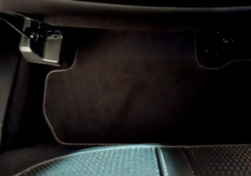Gros plan sur le tapis de sol noir avec surpiqûres blanches côté conducteur du Peugeot 3008 GT 2023.