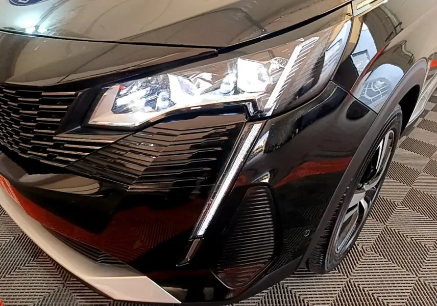 Gros plan sur l'avant droit noir brillant du Peugeot 3008 2023 avec phares LED et calandre distinctive.