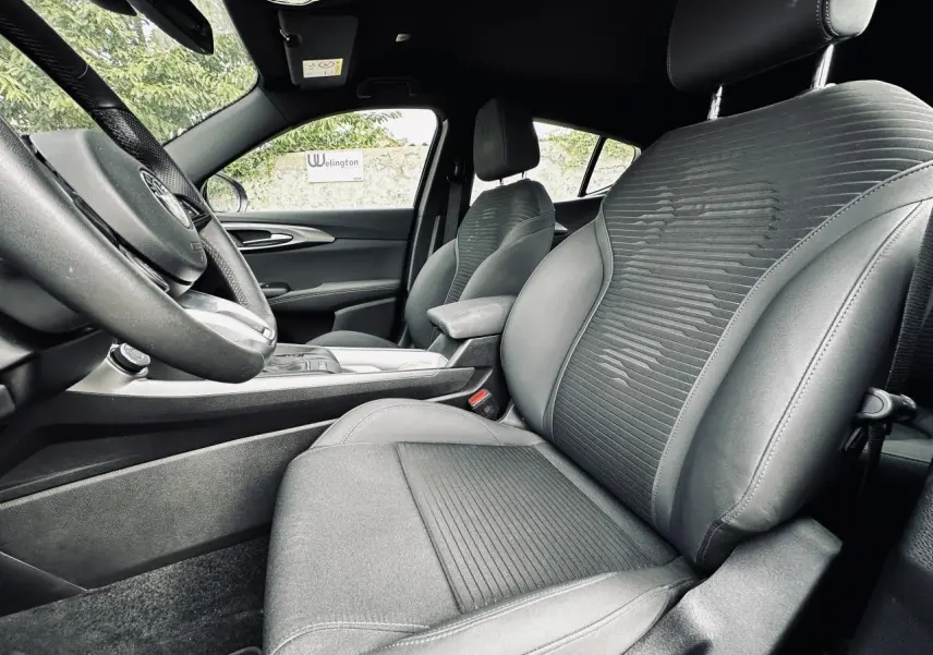 Vue intérieure côté gauche de l'Alfa Romeo Tonale 2024, sièges en cuir et tissu gris avec accoudoir central.