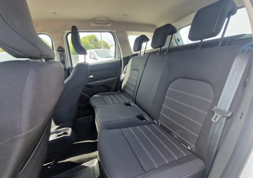 Vue intérieure côté droit des sièges arrière noirs du Dacia Duster blanc 4x4, soulignant l'espace et les appuie-têtes réglables.