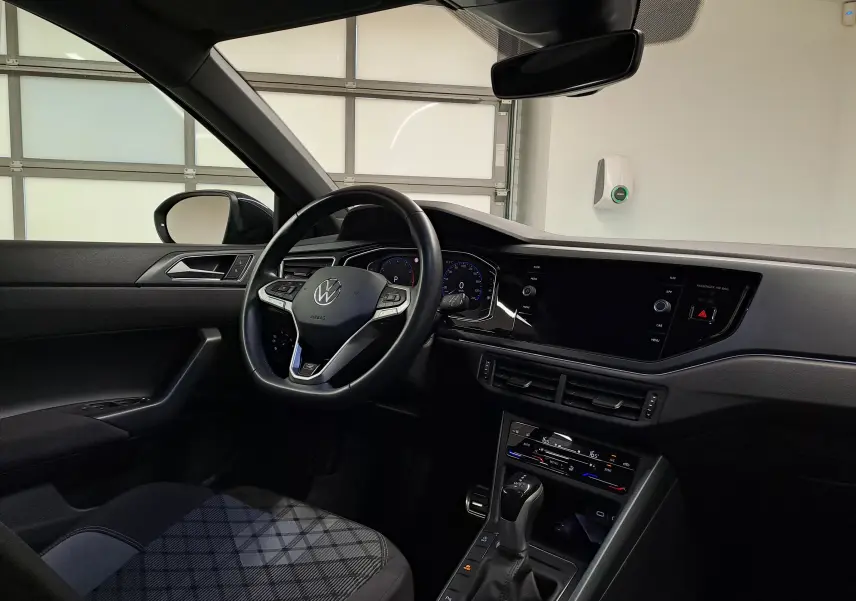 Vue intérieure côté conducteur du Volkswagen Taigo 2025 noir intense, volant multifonction et tableau de bord digital.
