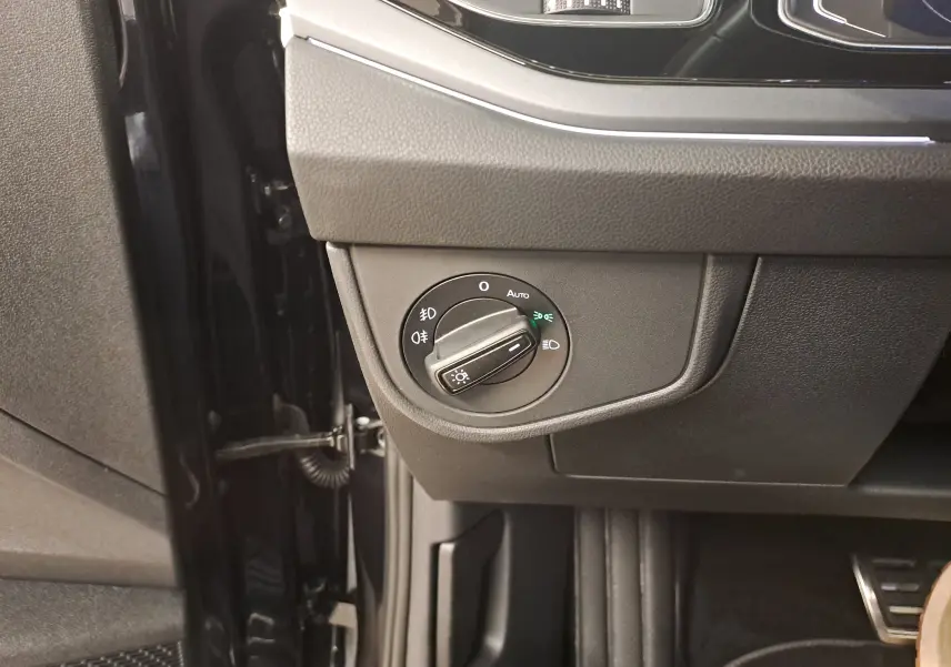 Gros plan sur le bouton de commande des phares du Volkswagen Taigo noir intense, côté gauche du tableau de bord.