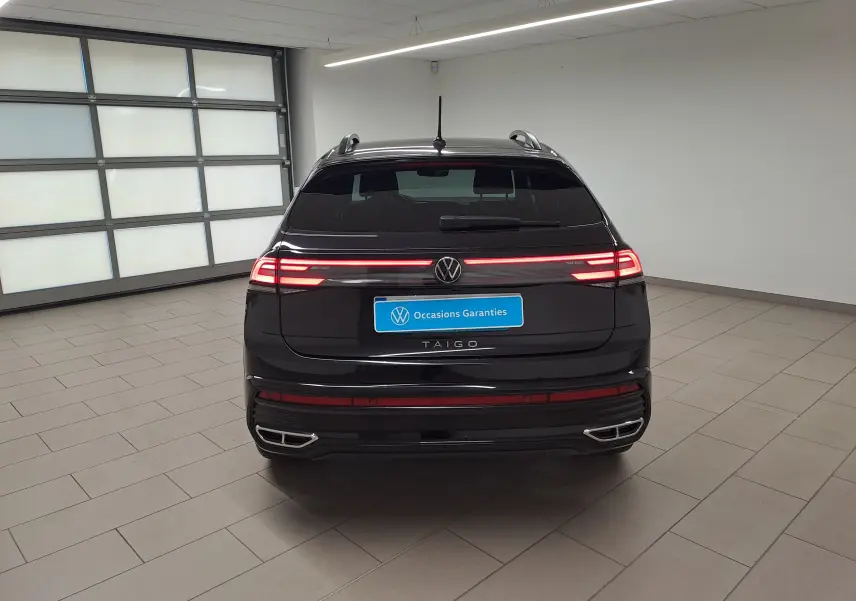 Vue arrière d’un Volkswagen Taigo noir intense 2025 avec feux LED allumés et double sortie d’échappement chromée.