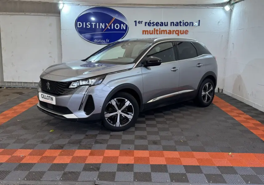 Peugeot 3008 BlueHDi 130 GT gris clair vue 3/4 avant droit en intérieur avec logo Distinxion en arrière-plan