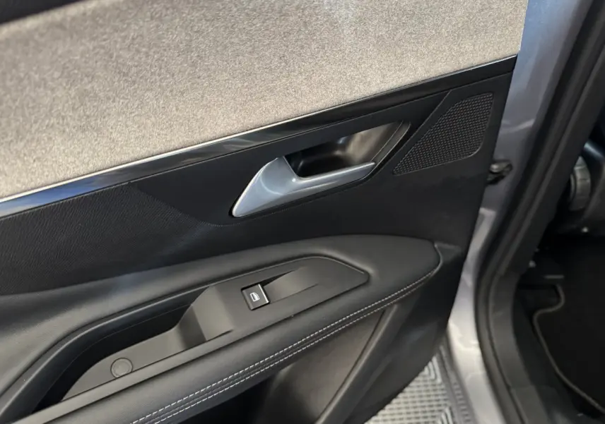 Gros plan sur la porte avant gauche gris clair du Peugeot 3008 avec poignée argentée et commande de vitre noire.
