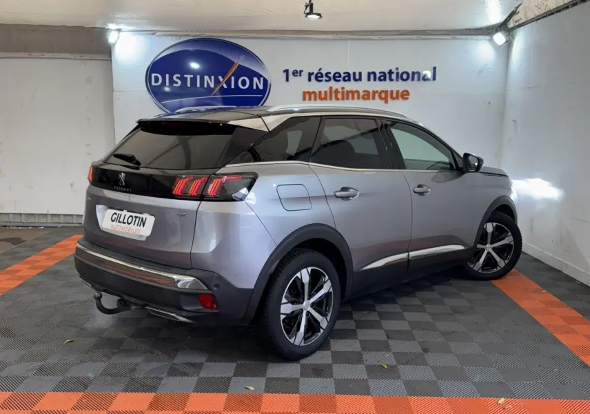 Peugeot 3008 BlueHDi 130 GT gris clair vue 3/4 arrière droit en intérieur avec toit noir et feux LED distinctifs.