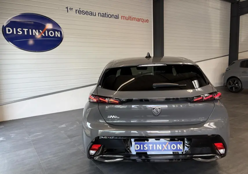 Vue arrière d'une Peugeot 308 GT 2025 gris selenium avec feux arrière à signature lumineuse griffe à griffe.