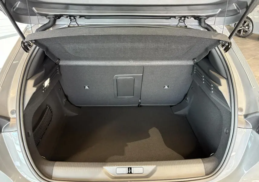 Coffre ouvert vu de l'arrière d'une Peugeot 308 gris selenium, intérieur spacieux et bien fini.