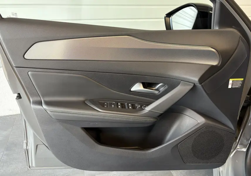 Porte avant gauche de Peugeot 308 GT 2025 gris Selenium, avec garniture noire et surpiqûres vertes visibles.