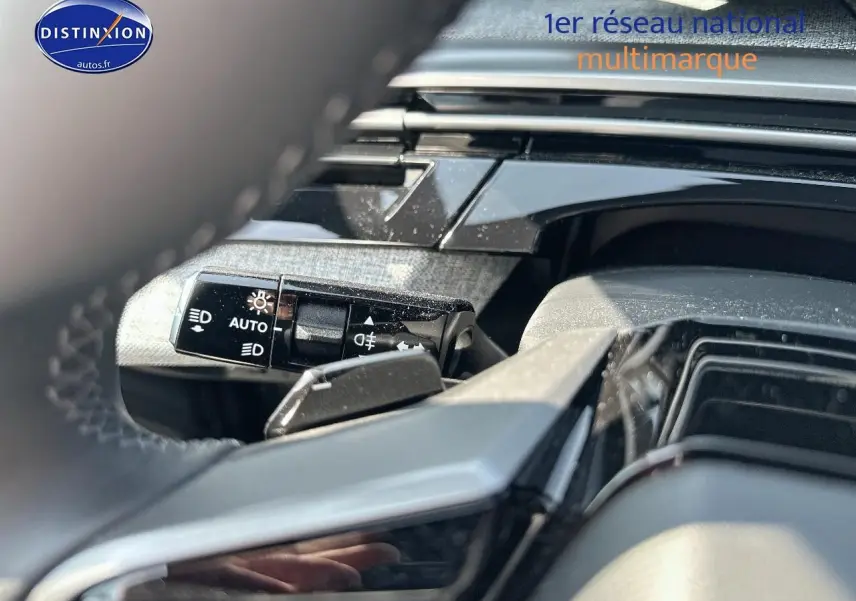 Détail du commodo d'éclairage sur le côté gauche du volant d'un Peugeot 3008 noir perla nera 2025.