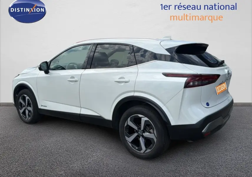 Vue 3/4 arrière côté droit d'un Nissan Qashqai blanc nacré métallisé avec jantes bi-ton et toit noir.