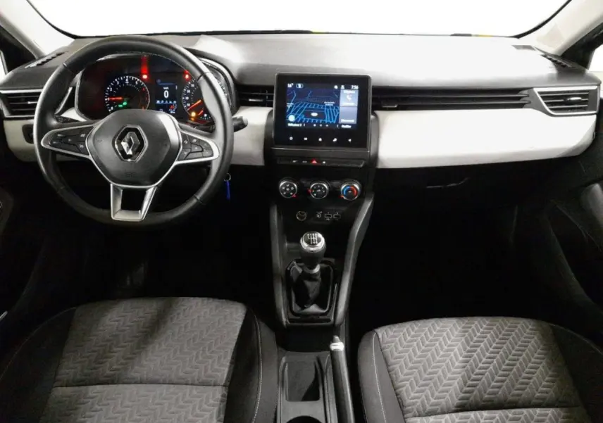 Vue intérieure avant centrée sur le tableau de bord et volant de la Renault Clio gris clair 2023 avec boîte manuelle.