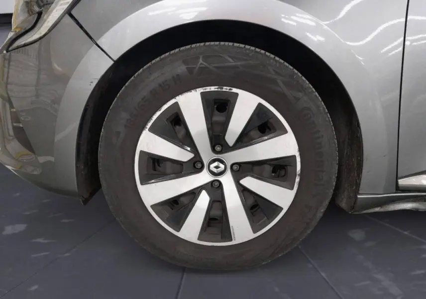 Gros plan sur la roue avant gauche gris clair d'une Renault Clio 2023 avec jante à motifs noirs et argentés.