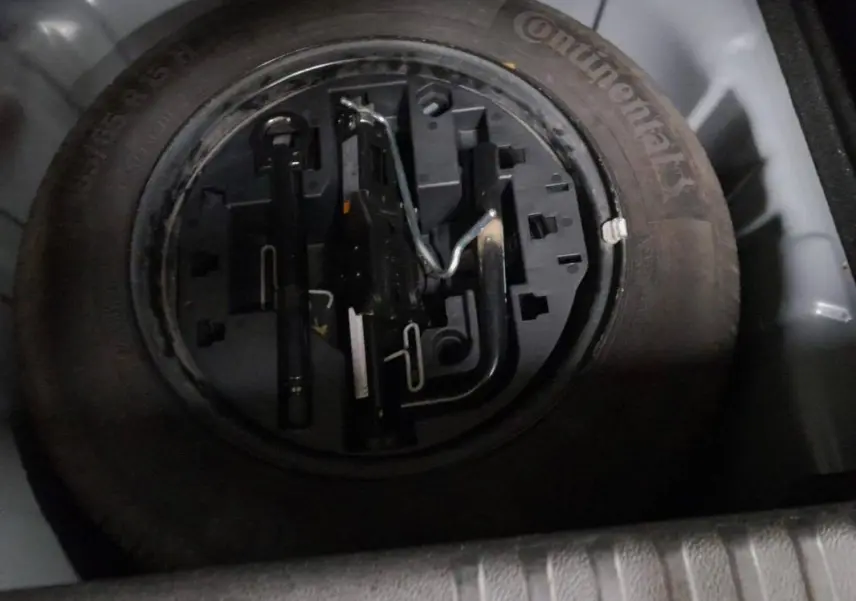 Gros plan sur la roue de secours et les outils de bord dans le coffre d'une Renault Clio gris clair 2023.