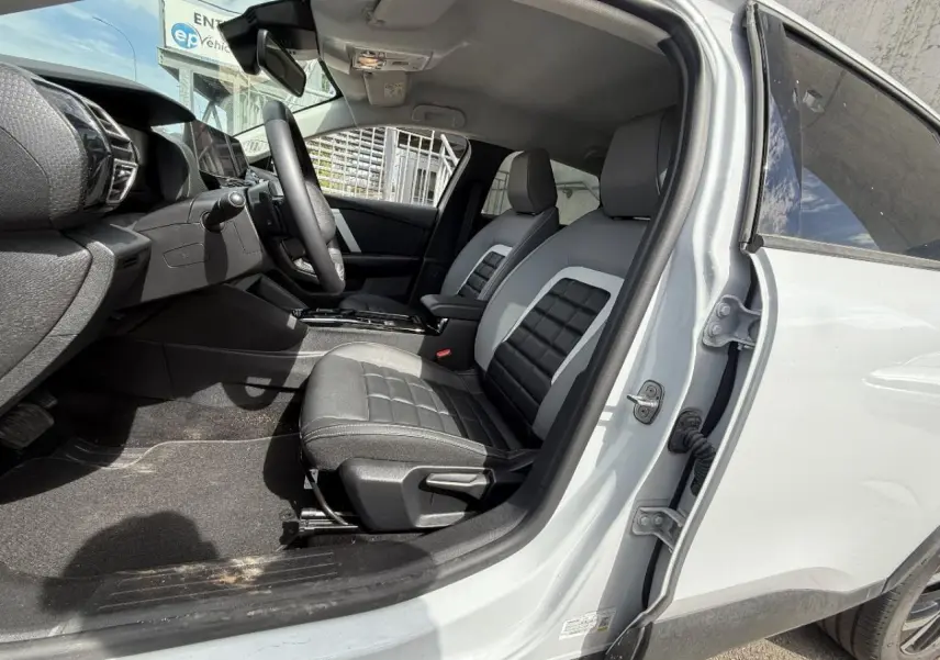 Vue intérieure côté conducteur d'une Citroën C4 blanc okenite 2025, montrant les sièges avant et le tableau de bord.