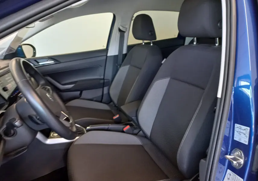 Vue intérieure côté conducteur du Volkswagen Taigo bleu récif 2025, montrant les sièges avant en tissu noir et gris.