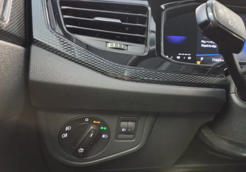 Gros plan sur la commande des phares côté gauche du tableau de bord du Volkswagen Taigo 2025 en bleu récif.